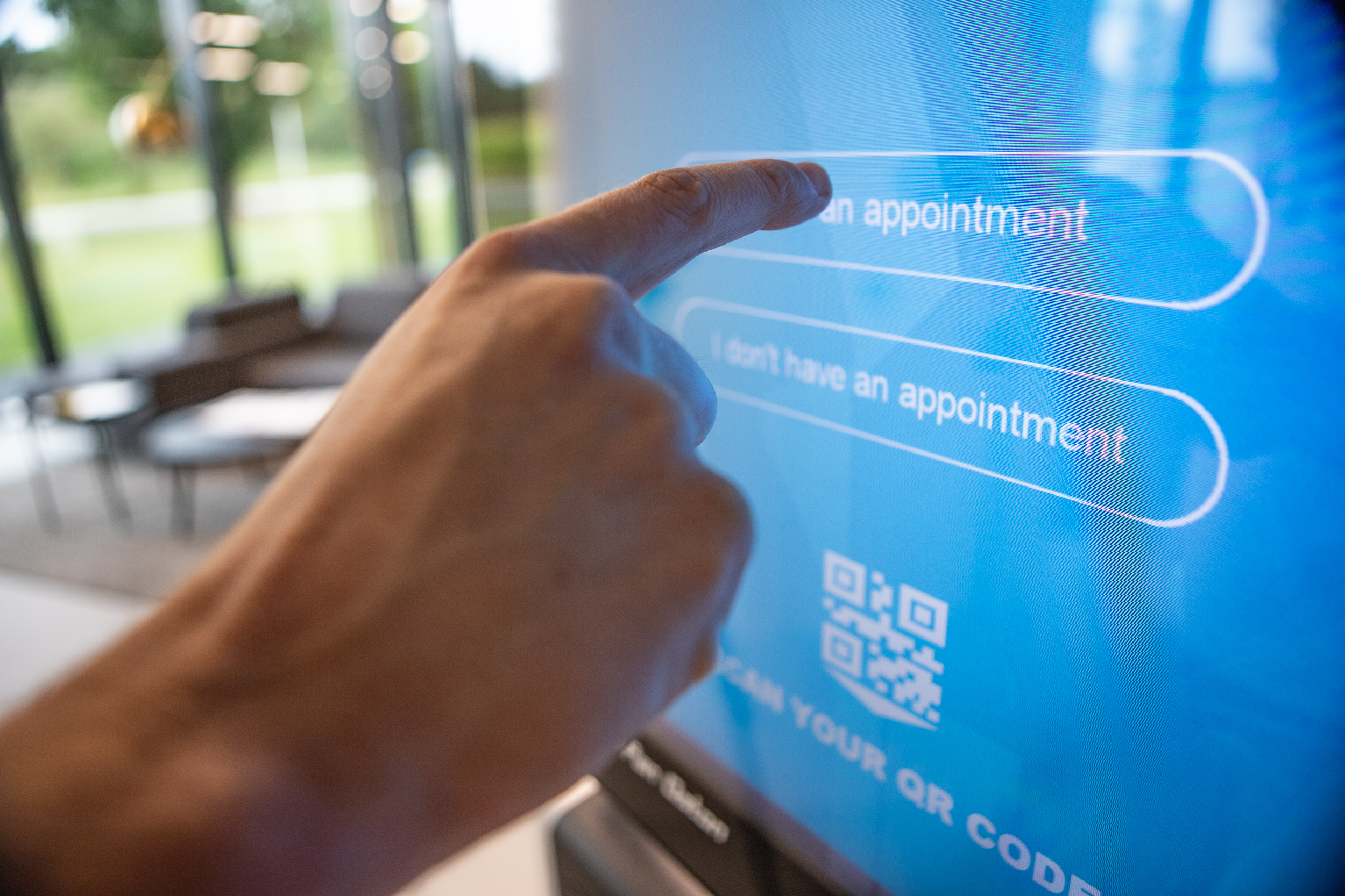 En människa pekar med sitt finger på en touch-skärm som säger 