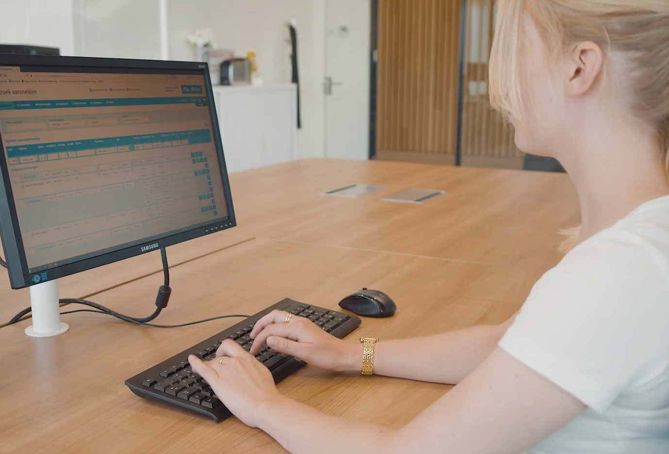 En kvinna sittandes vid en dator med ett receptionssystem öppet